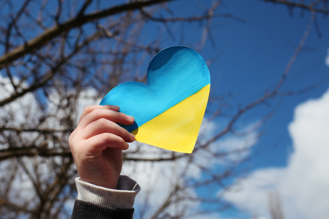 A child holds a heart with a drawn Ukrainian flag